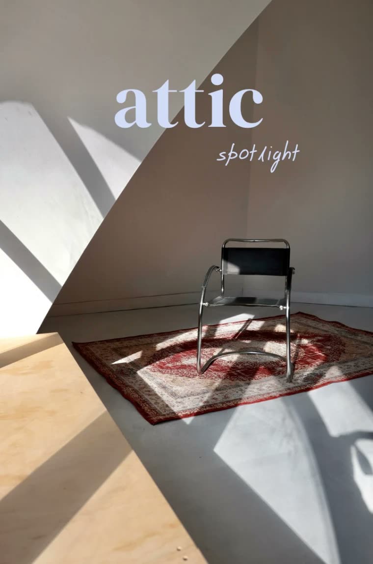 Ateliér Attic Studia v podkroví: kovová stolička na perzskom koberci v ostrom slnečnom svetle, nápis attic spotlight.