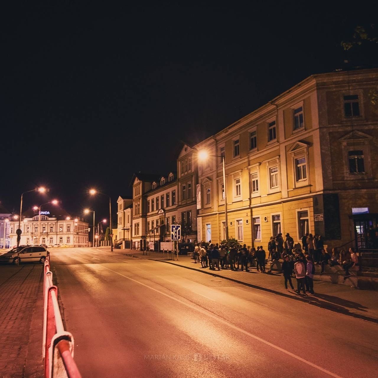 Nočná ulica v Trenčíne, pred klubom Stejdž stojí dlhý rad ľudí.