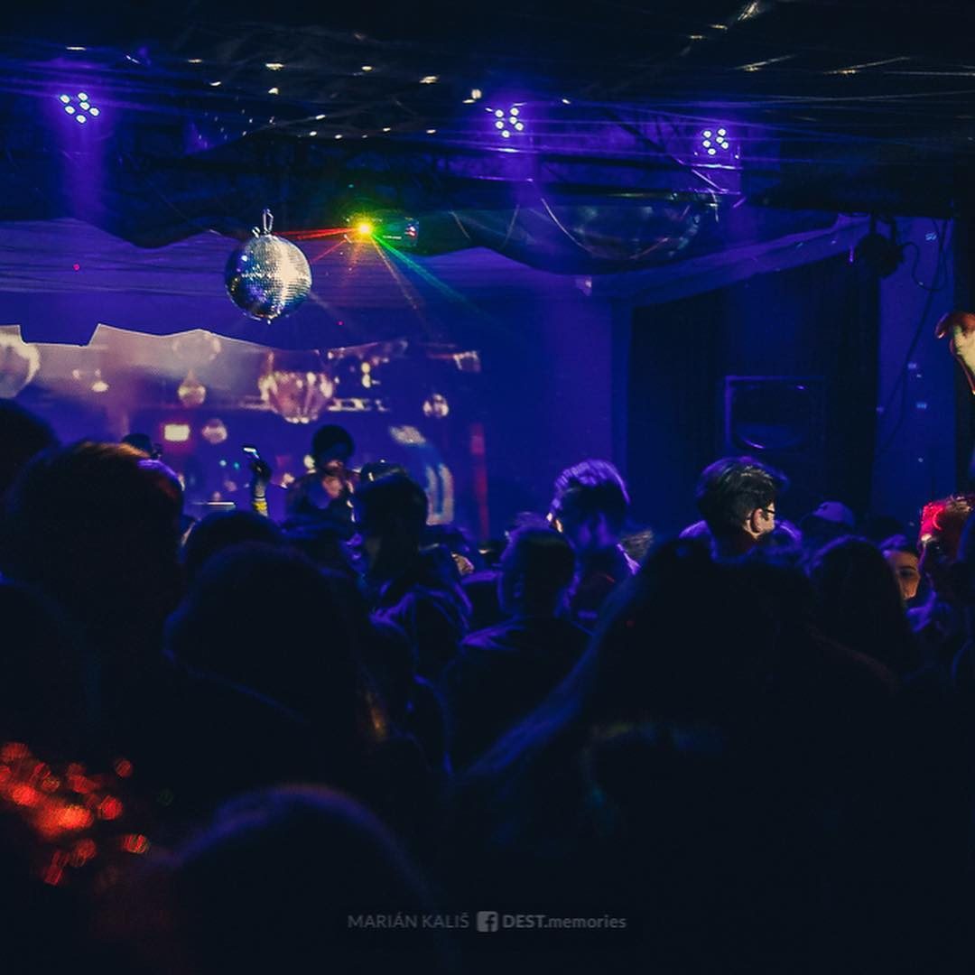 Disko guľa a modré svetlá nad davom pred pódiom.