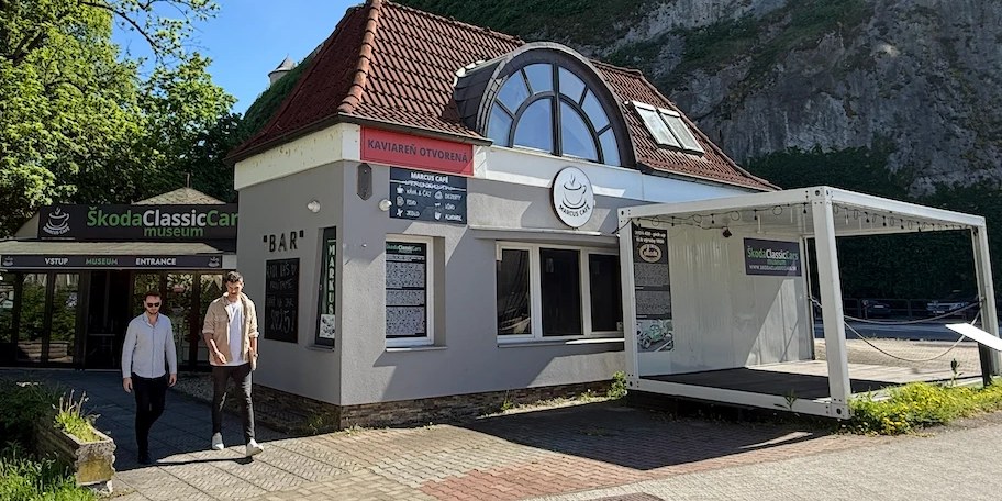 Budova pred rekonštrukciou: sivá fasáda s nápisom Marcus Café, vedľa vstup do Škoda Classic Car múzea.